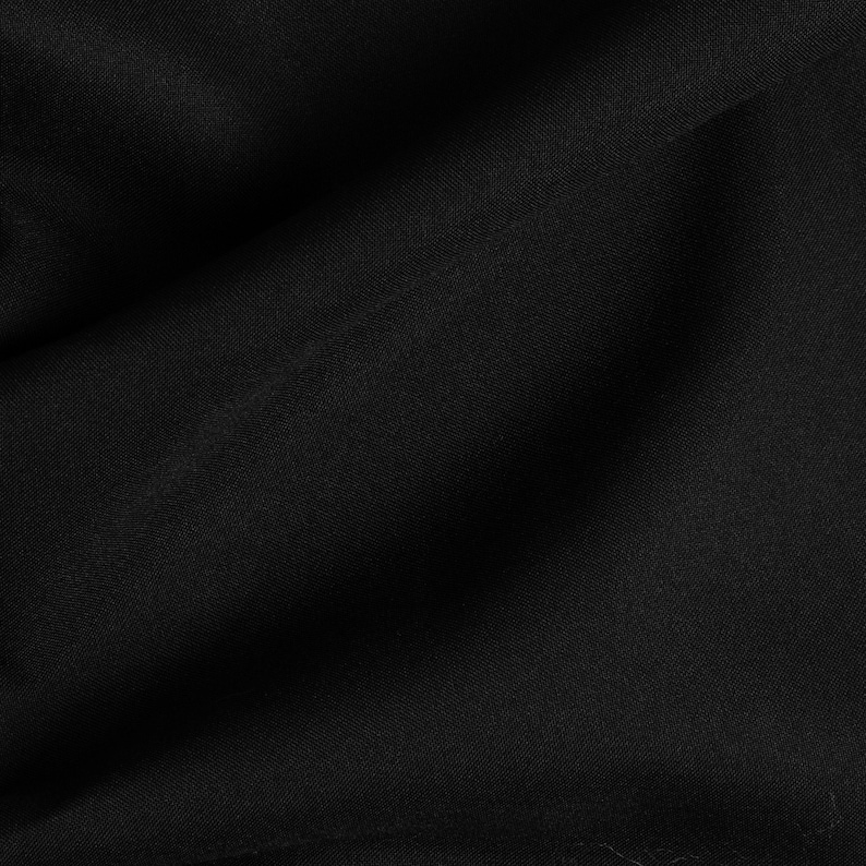 Puede incluir: Primer plano de una tela negra con una textura lisa y uniforme. La tela est&aacute; ligeramente arrugada, creando un patr&oacute;n sutil.
