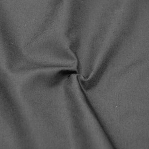 May include: A close-up of a dark grey fabric with a smooth texture. The fabric is folded and creased, creating a soft, flowing look.