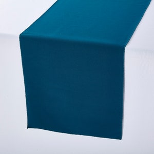 May include: Teal table runner. The runner is made of a smooth, silky fabric and is perfect for adding a touch of color to your table setting.