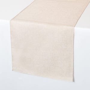 May include: A beige table runner with a subtle textured pattern. The runner is made of a soft, woven fabric and is perfect for adding a touch of elegance to any table setting.