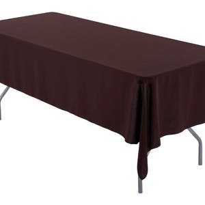 May include: A rectangular brown tablecloth draped over a folding table with silver legs. The tablecloth is a solid color and covers the entire table surface, with the edges hanging down.