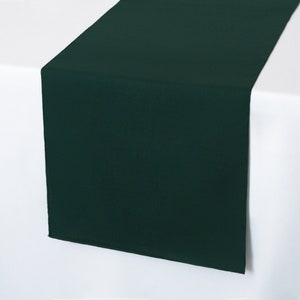 May include: A dark green table runner. The runner is made of a smooth fabric and is perfect for adding a touch of elegance to any table setting.