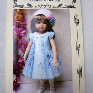 May include: A pattern for a pleated hanky dress for 10" to 16" dolls. The pattern is shown on a doll wearing a blue dress with a white lace collar and a white hat with a pink flower.