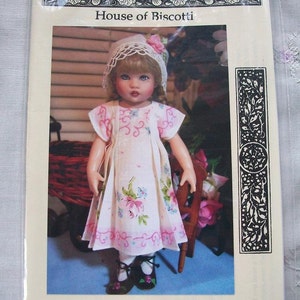 May include: A doll wearing a white dress with pink flowers and a white lace bonnet. The doll is sitting on a wooden chair with a pink and white floral pattern. The doll is 7 to 8 inches tall. The image is from House of Biscotti and is for a Hanky Pattern.