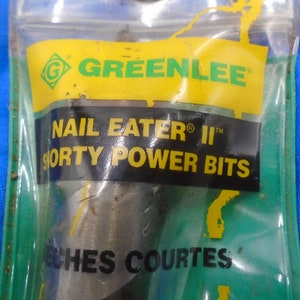 Puede incluir: Un primer plano de un paquete que contiene una broca Greenlee Nail Eater II Shorty Power Bits. El paquete es amarillo y verde con el texto "Greenlee", "Nail Eater II", "Shorty Power Bits" y "Inches Courtes".
