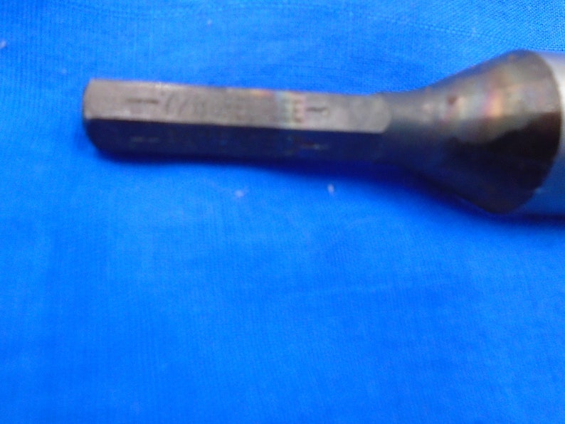 Puede incluir: Primer plano de una herramienta de metal plateado con cabeza hexagonal. La herramienta tiene un mango negro y est&aacute; ligeramente curvada.