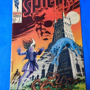 May include: A comic book cover featuring Nick Fury, Agent of S.H.I.E.L.D. The cover art depicts Nick Fury in a red and black suit, with a red background and a white moon. The cover also features a graveyard scene with a blue dog and a tombstone that reads "Black Ravenluck 1758-1805".