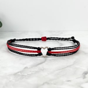 May include: A black and red friendship bracelet with a silver heart charm.