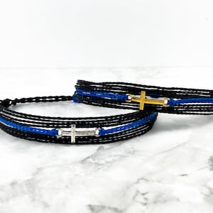 May include: Two friendship bracelets with black and blue cords and silver and gold cross charms.