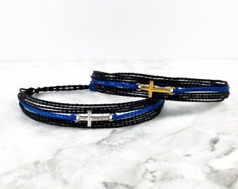 May include: Two friendship bracelets with black and blue cords and silver and gold cross charms.