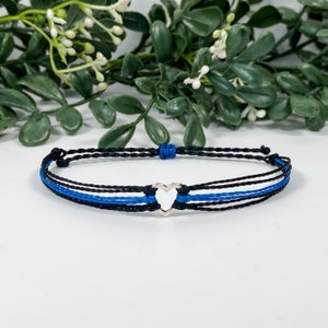 May include: A blue and black friendship bracelet with a silver heart charm.