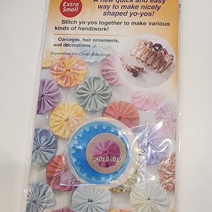 May include: A blue and white plastic yo-yo maker with the text "Quick" Yo-Yo Maker, "Faiseur de Yo-Yo "Rapido", "Rapido", Molde para hacer Yo-Yos, Jo-Jo-Schablone, Rapido' printed on the packaging. The packaging also includes the text "Extra Small" and "A new quick and easy way to make nicely shaped yo-yos!" The packaging shows a variety of colorful yo-yos made with the maker.