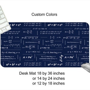 Peut inclure: Un tapis de bureau bleu foncé avec un motif de formules mathématiques blanches. Le tapis est disponible en trois tailles : 18 x 36 pouces, 14 x 24 pouces et 12 x 18 pouces.