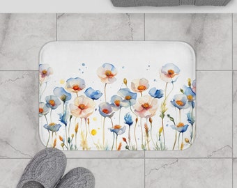 May include: White bath mat with a watercolor floral design featuring blue and pink flowers. The mat measures 24 inches by 17 inches.