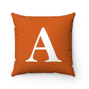 May include: Orange cushion with a white letter A in the centre.