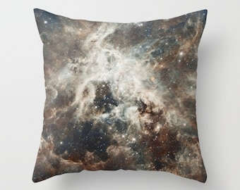 May include: Square throw pillow featuring a detailed image of a nebula in shades of brown, white, and blue. The celestial design includes swirling clouds of gas and dust with numerous bright stars, creating a cosmic theme.