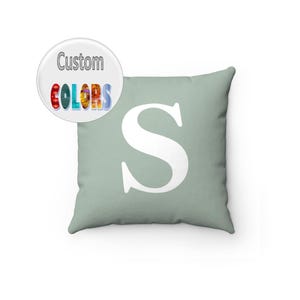 May include: A light green throw pillow with a white capital letter "S" in the center.