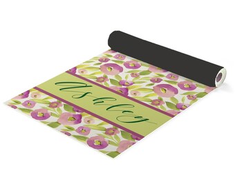 May include: A green and purple floral yoga mat with the name "Ashley" printed on it in a green script font.