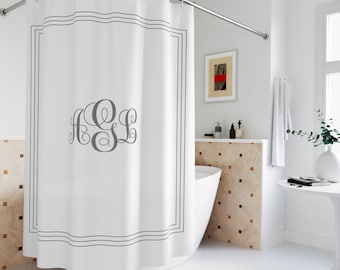 May include: White shower curtain with a gray monogram and a gray border. The curtain hangs from a curved, silver-colored shower rod. The bathroom has a white tub and a small table with a vase.