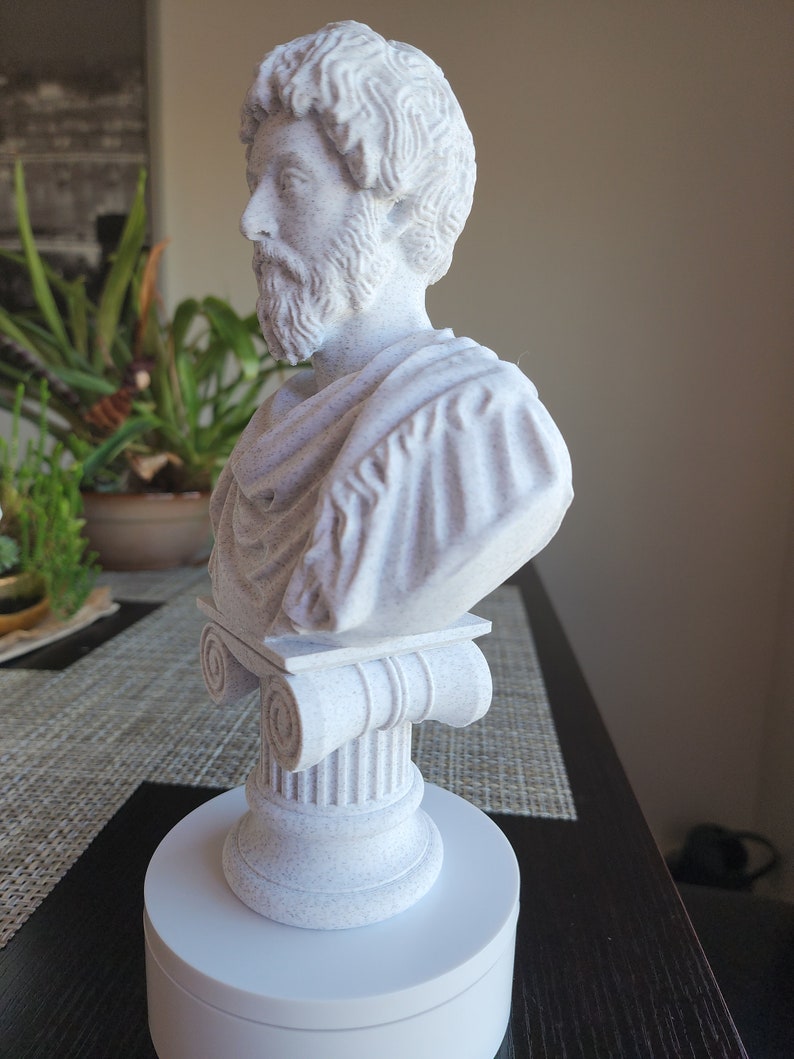 Puede incluir: Busto de escultura blanca de un hombre con barba, vistiendo una toga, sobre un pedestal blanco con una base de columna.