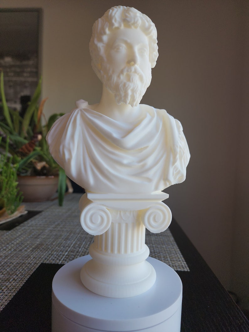 Puede incluir: Busto de escultura blanca de un hombre con barba, vistiendo una toga, sobre un pedestal blanco con una base de columna.