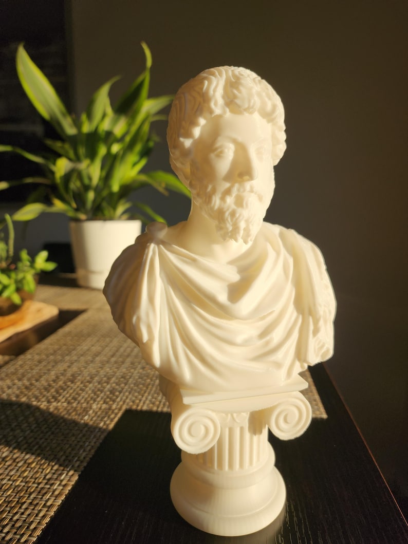 Puede incluir: Busto de yeso blanco de un hombre con barba y pelo corto. El busto est&aacute; sobre un pedestal blanco con un dise&ntilde;o de columna estriada.