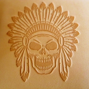 May include: A leather stamp with a design of a skull wearing a headdress with feathers.