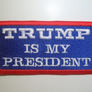 May include: A blue and red embroidered patch with white text that reads "TRUMP IS MY PRESIDENT".