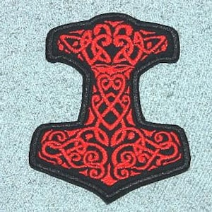 May include: Embroidered patch featuring a red Mjolnir hammer design with intricate knotwork on a black border. The patch is in the shape of Thor's hammer, a symbol of Norse mythology.