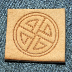 May include: A brown leather stamp with a Celtic knot design. The knot is a circle with four interlocked loops.