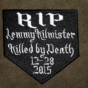 May include: Black and white embroidered patch with the text "RIP Lemmy Kilmister Killed by Death 12-28 2015".