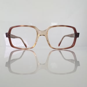 May include: A pair of brown and beige rectangular eyeglasses with a clear lens.