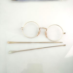 Pode incluir: Óculos redondos dourados com dobradiça de mola e duas ferramentas de metal dourado para ajustar os óculos.