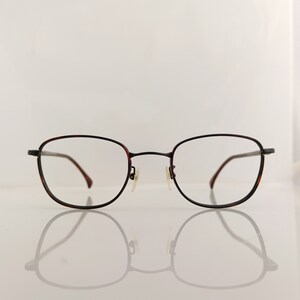 Puede incluir: Un par de gafas de pasta rectangulares de color marrón y negro.