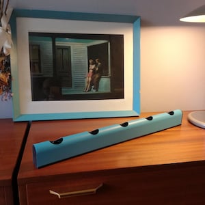 May include: A light blue wall mounted magazine rack with five slots. The rack is made of metal and has a modern design.