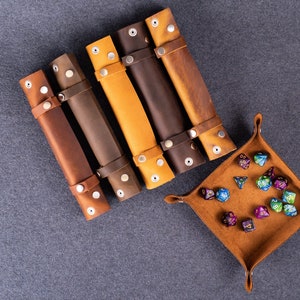 May include: Five brown leather dice rolling trays with metal snaps and a brown leather dice tray with colorful dice.