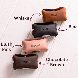 May include: Five leather pouches in different colors, each with a name embossed on the front. The colors are: whiskey, black, blush pink, chocolate brown, and basil.