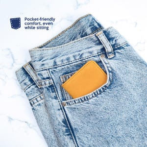 May include: A yellow leather wallet in the front pocket of a pair of light blue denim jeans. "Pocket-friendly comfort, even while sitting" is written in blue text on a white background.