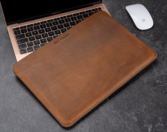 May include: A brown leather laptop sleeve with the text "NOT YOURS" embossed on the front.