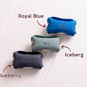 May include: Three leather dog collar covers in different colors: royal blue, iceberg green, and blueberry. The covers have the names "Loki", "Milo", and "Casper" embossed on them.