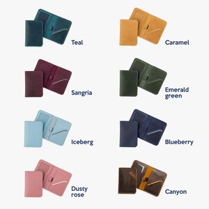 May include: Six different colored leather wallets, each with a separate flap, laid out on a white background. The colors are teal, caramel, sangria, emerald green, iceberg, blueberry, dusty rose, and canyon.