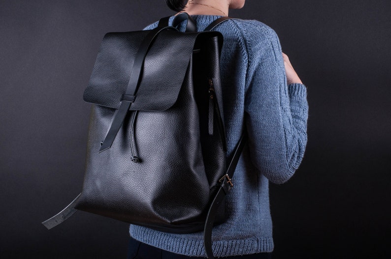 May include: A black leather backpack with a drawstring closure and a zippered pocket on the front.