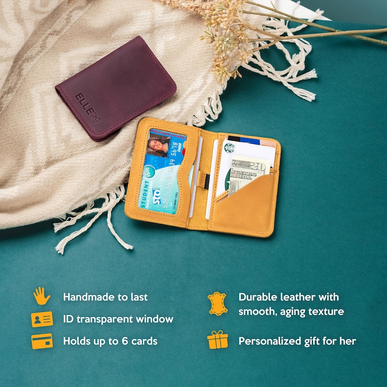 May include: A yellow leather wallet with a transparent window for an ID card. The wallet is open and has several cards inside. The wallet is on a teal surface with a white blanket and a small purple leather wallet in the background.
