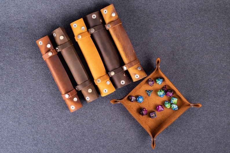 May include: Five brown leather dice rolling trays with metal snaps and a brown leather dice tray with colorful dice.