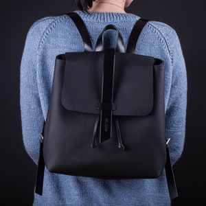 May include: A black leather backpack with a flap closure and adjustable straps.