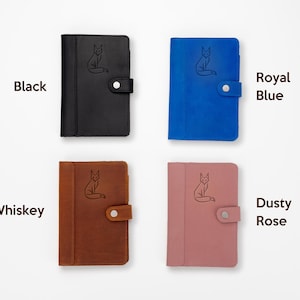 Pode incluir: Quatro cadernos de couro em preto, azul royal, whisky e rosa empoeirado. Cada caderno apresenta uma ilustra&ccedil;&atilde;o de raposa e um fecho de press&atilde;o. As cores s&atilde;o rotuladas com texto: Preto, Azul Royal, Whisky e Rosa empoeirado.