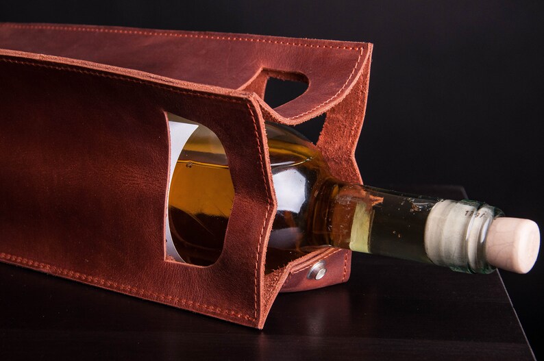 Handcrafted leather wine bottle holder with structured interior, personalized anniversary wine carrier for couples shown holding standard wine bottle