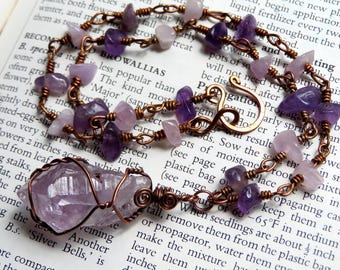 May include: A copper wire wrapped necklace with a large amethyst pendant and smaller amethyst and rose quartz beads.