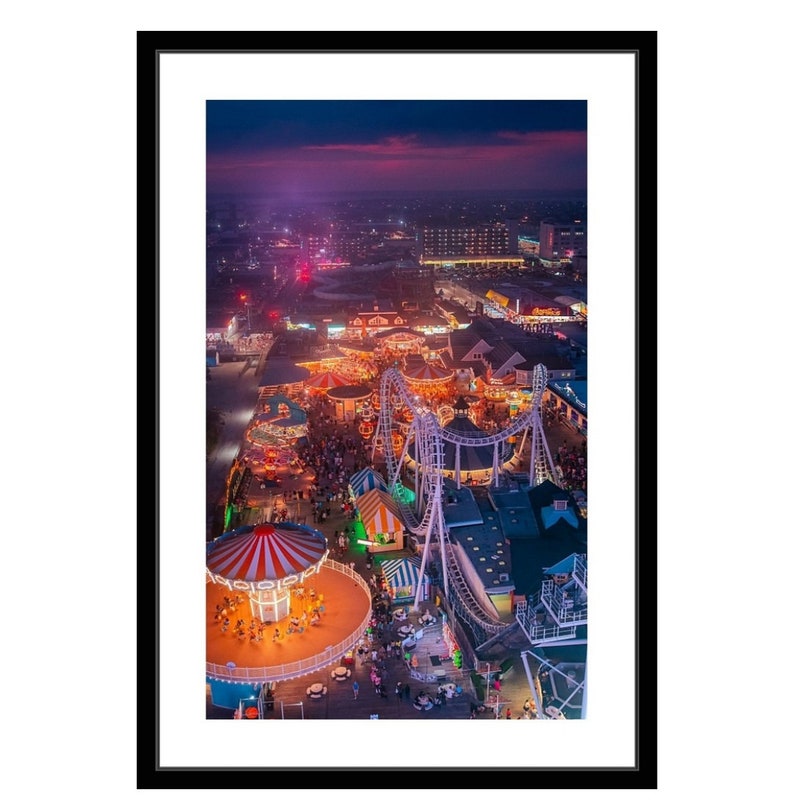 May include: An aerial view of a brightly lit amusement park at night. The park is filled with colorful rides, including a carousel, a roller coaster, and various other attractions. The lights create a festive atmosphere, and the park is bustling with activity.