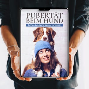 Könnte beinhalten: Ein digitales Tablet mit einem Buchcover, das den Titel PUBERTÄT BEIM HUND und den Untertitel Deinen Junghund besser verstehen trägt. Das Cover zeigt eine Person mit einer blauen Mütze und einem braun-weißen Hund auf den Schultern.